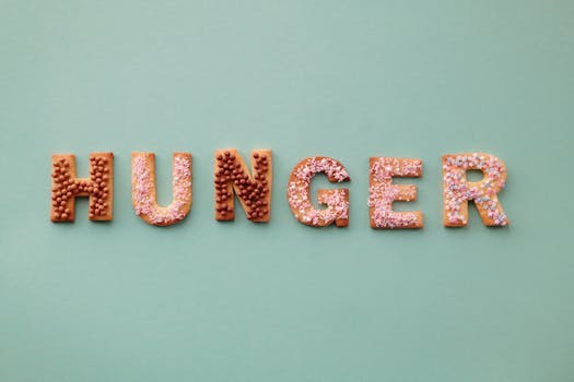 Colorful cookies spelling the word 'Hunger' on a pastel background, topped with sprinkles.