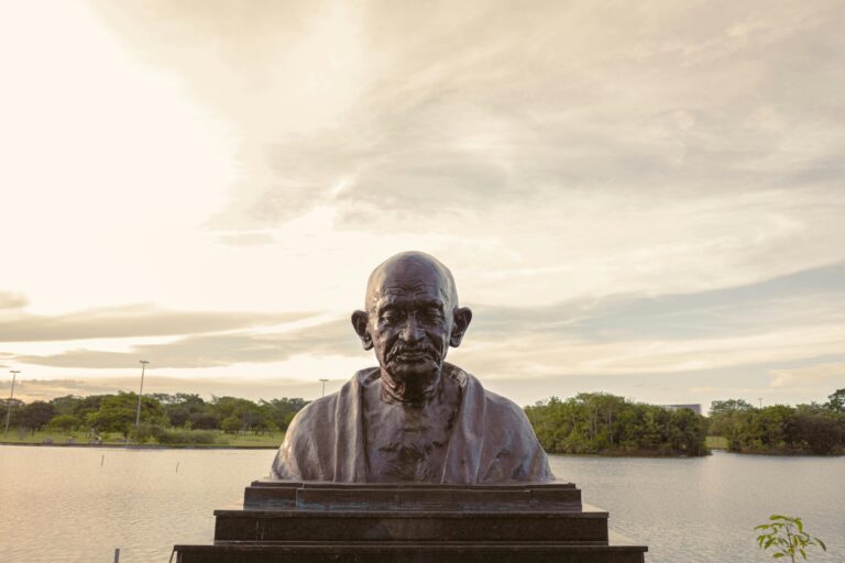 Bronze bust of Mahatma Gandhi with serene lake backdrop in Brasília, Brazil.